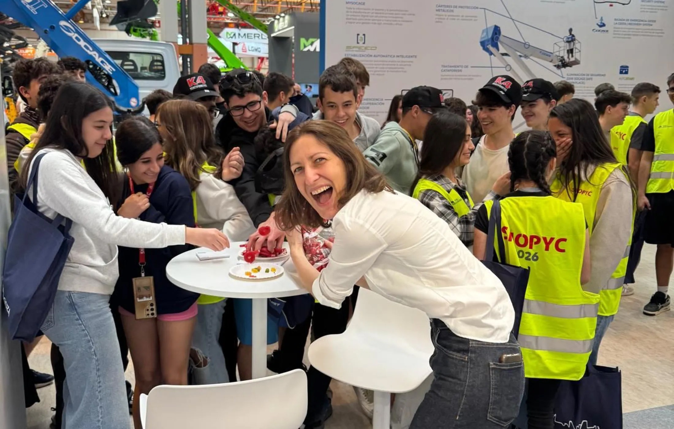 Platform Parts representative engaging with students at a busy trade fair stand featuring aerial work platform displays.