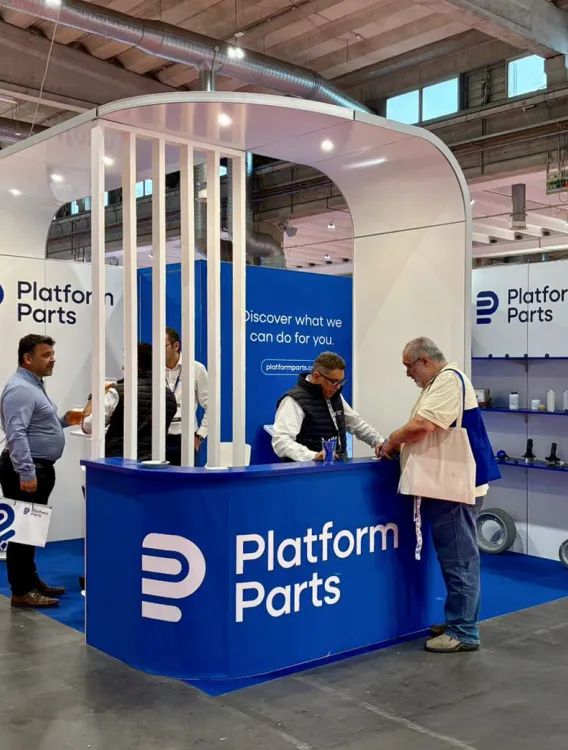 Platform Parts exhibition booth at a trade show, with staff members assisting visitors and product displays showcasing aerial work platform components.